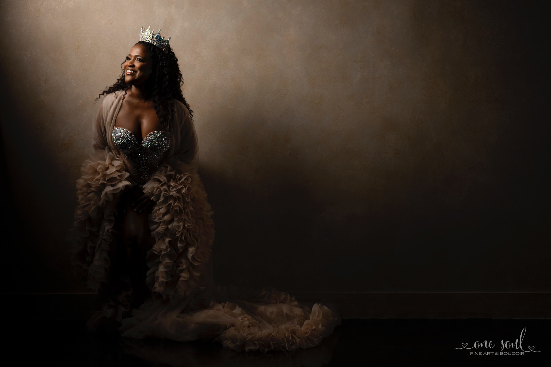 Ava Kay Rose wearing a crown and a dramatic ruffled gown in a fine-art studio portrait